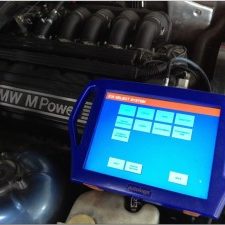 Diagnostic tool displaying information next to a BMW engine.