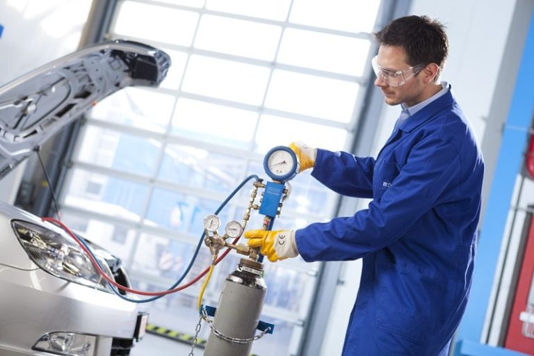 A technician carrying out a nitrogen pressure test on a car's AC.